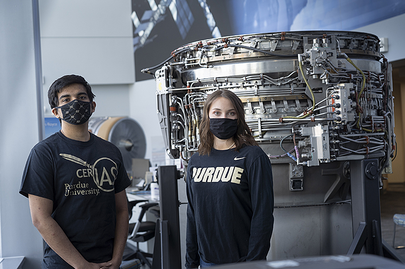 Kaitlyn Knabe, a junior cybersecurity student in the Purdue Polytechnic Institute, and Vijay Sundararajan, a graduate student in Purdue’s Interdisciplinary Cybersecurity degree program, stand in front of a Rolls-Royce lift fan on display at the Purdue Technology Center Aerospace building